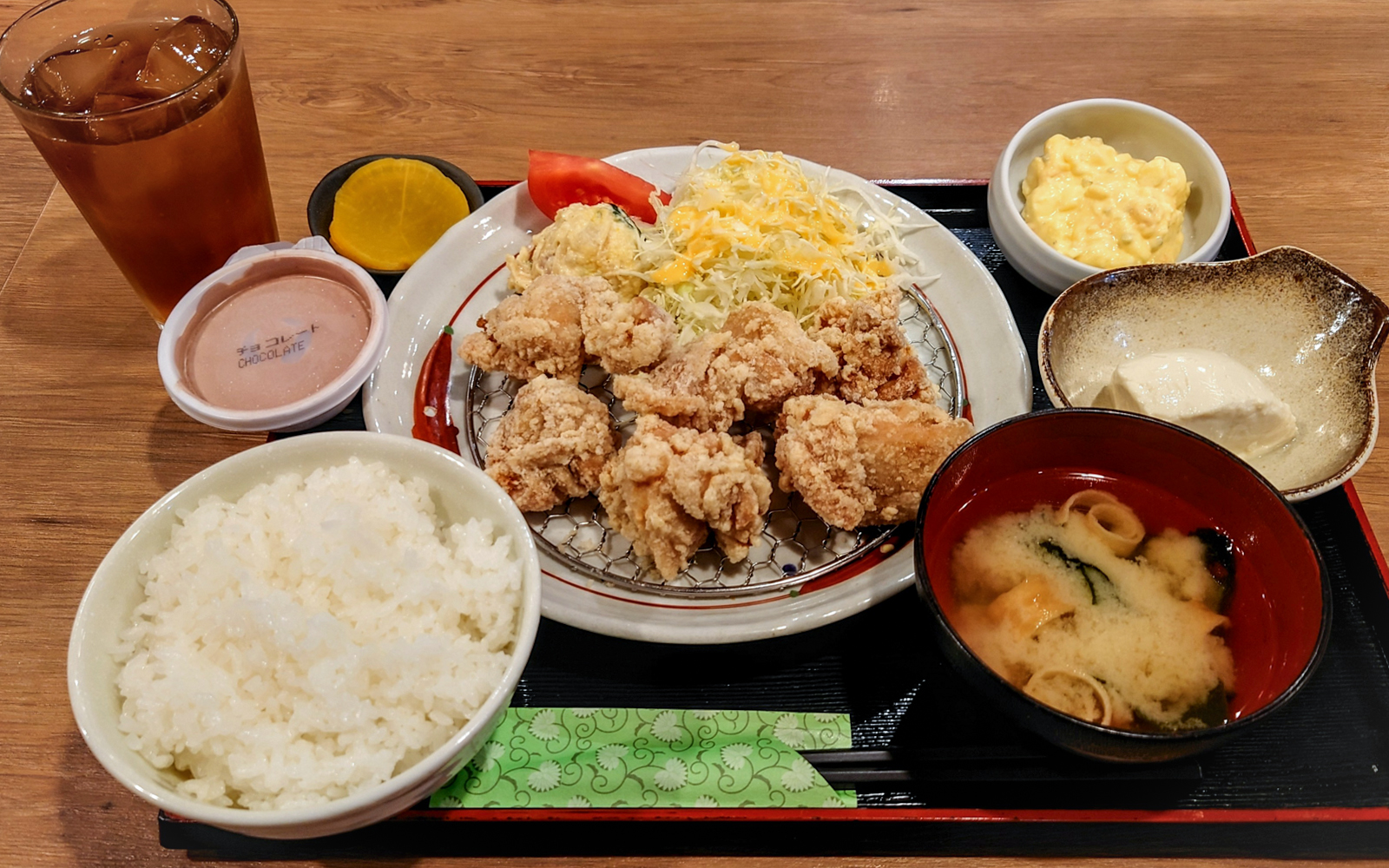 Traditional Japanese pub lunch with fried chicken, rice, miso soup, and side dishes.