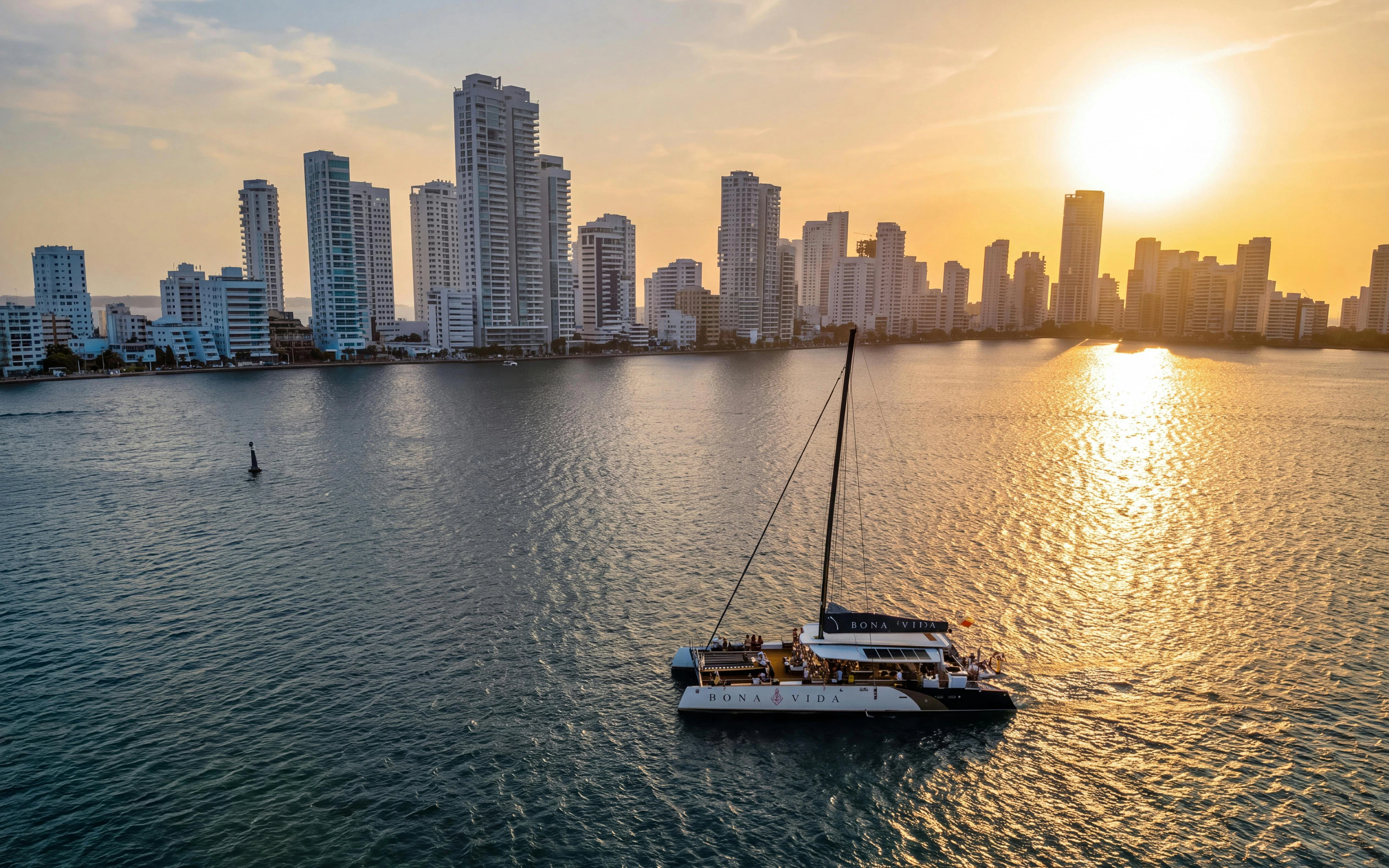 Catamaran sailing at sunset with Cartagena skyline in the background.