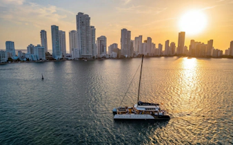 Catamaran sailing at sunset with Cartagena skyline in the background.