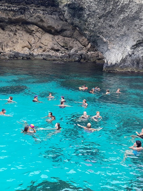 People swimming in the clear blue waters of the Blue Lagoon, Malta.