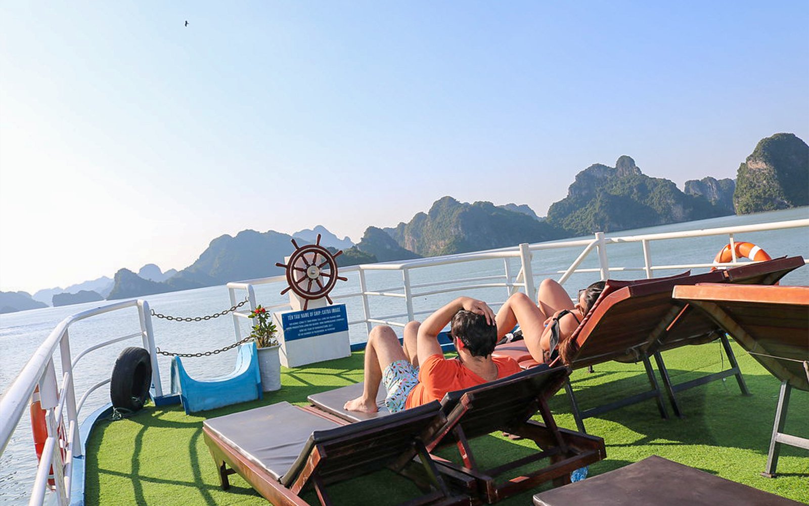 Passengers relaxing on the Dragonfly Standard Cruise deck with scenic views of limestone islands.