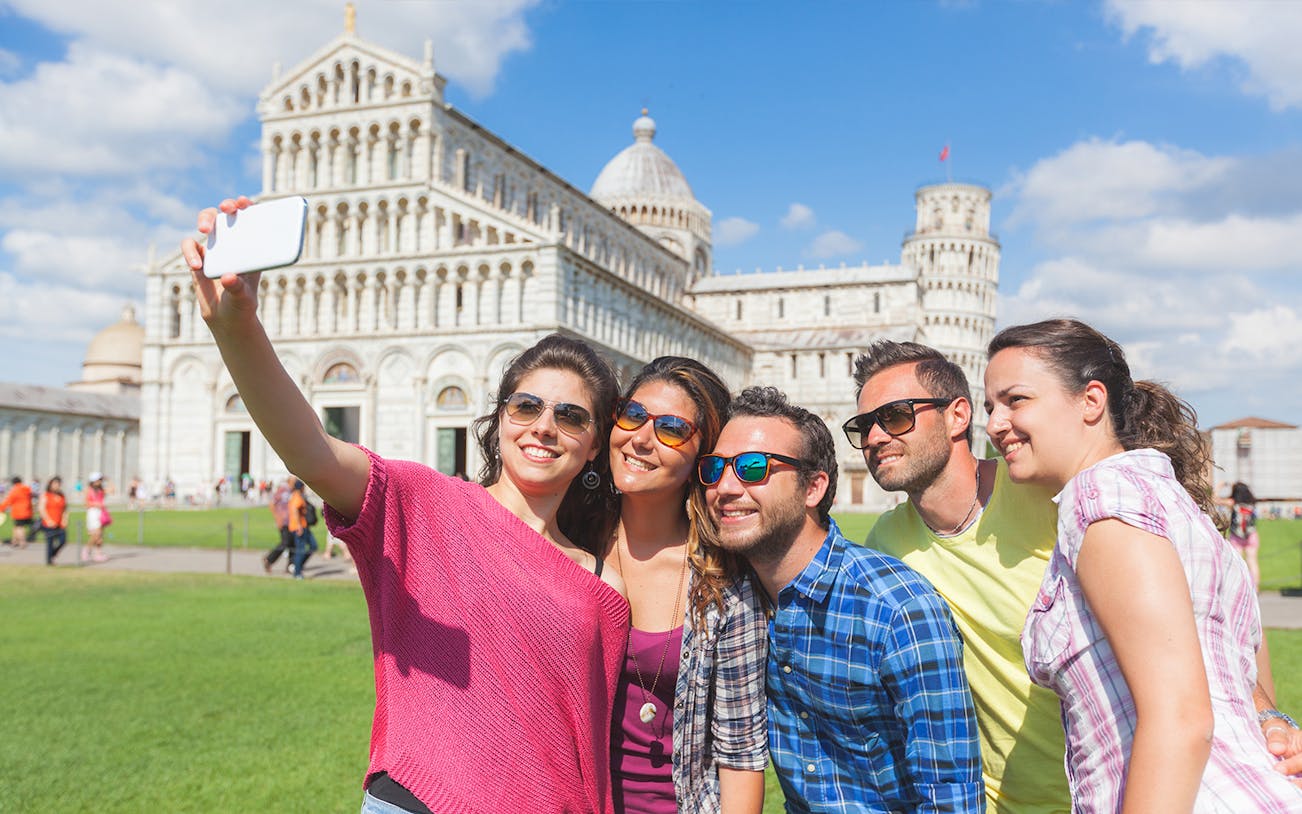 Group taking selfie in front of Pisa Cathedral during guided tour and wine tasting.