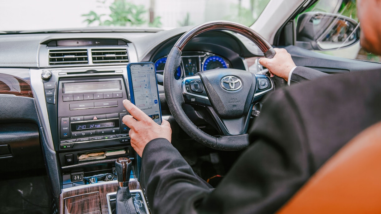 Driver using GPS navigation in car for private transfer between Bangkok and airport.