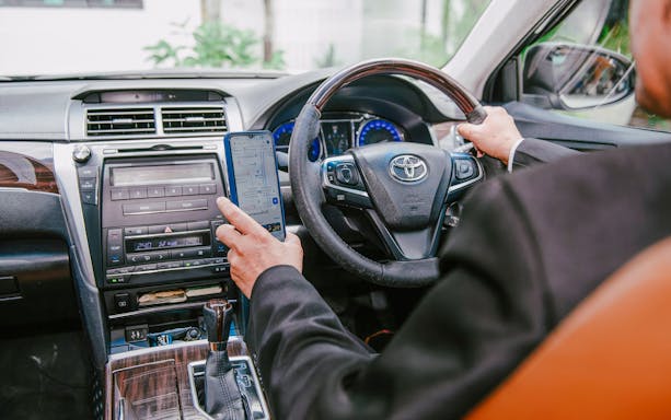 Driver using GPS navigation in car for private transfer between Bangkok and airport.