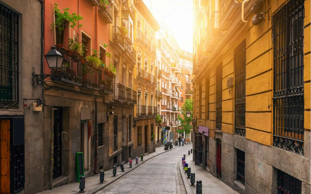 Narrow street in Madrid with historic buildings and balconies, part of a self-guided city exploration game.