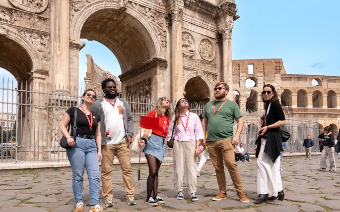 Tour group exploring the Arch of Constantine near the Colosseum in Rome.