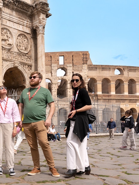 Tour group exploring the Arch of Constantine near the Colosseum in Rome.