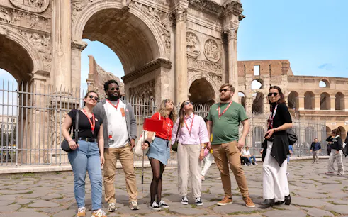 Tour group exploring the Arch of Constantine near the Colosseum in Rome.