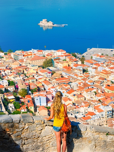 Tourist overlooking Nafplio cityscape and sea in Greece.