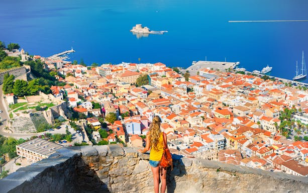 Tourist overlooking Nafplio cityscape and sea in Greece.
