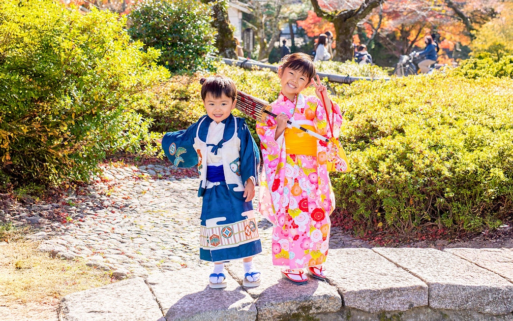 Kids in traditional kimono in Kyoto Arashiyama garden.