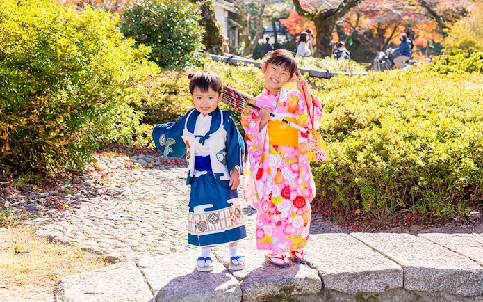 Kids in traditional kimono in Kyoto Arashiyama garden.