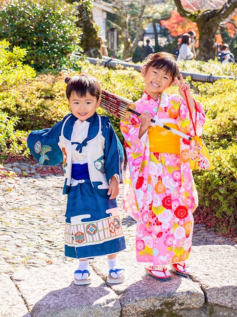 Kids in traditional kimono in Kyoto Arashiyama garden.