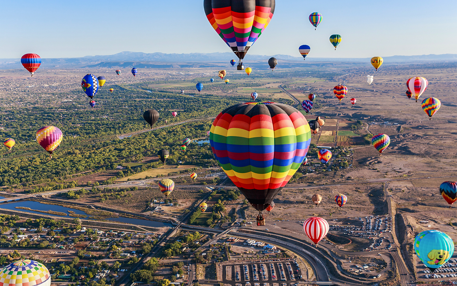 Hot air balloons floating over Albuquerque landscape during annual festival.