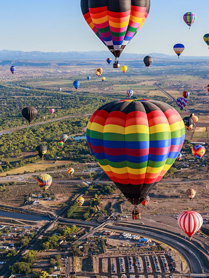 Hot air balloons floating over Albuquerque landscape during annual festival.