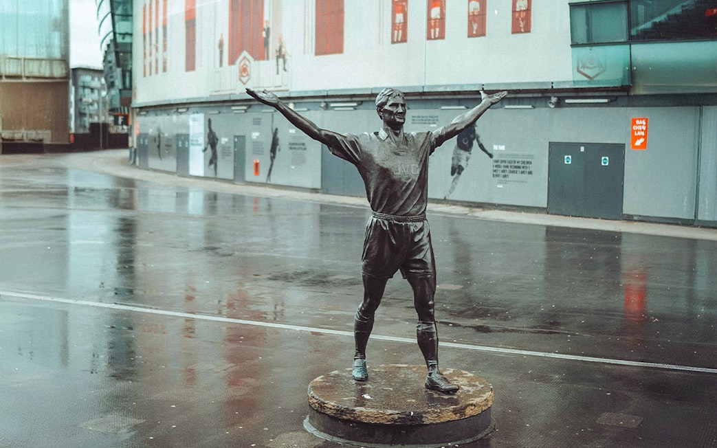 Statue of a footballer with arms raised outside the Emirates Stadium, London.
