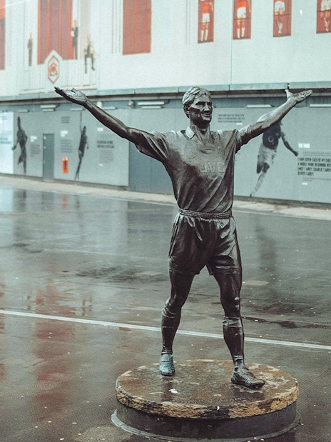 Statue of a footballer with arms raised outside the Emirates Stadium, London.