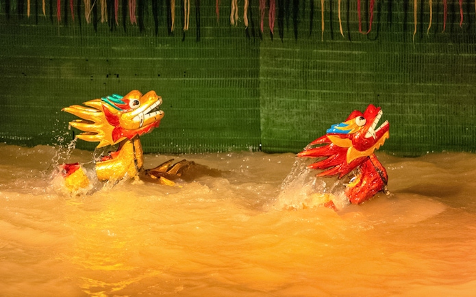 Golden dragon puppets performing in water at the Golden Water Puppet Show.
