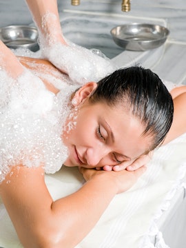 Person receiving a traditional Turkish bath massage with soap bubbles in Istanbul.
