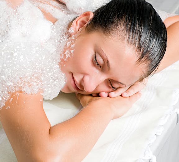 Person receiving a traditional Turkish bath massage with soap bubbles in Istanbul.