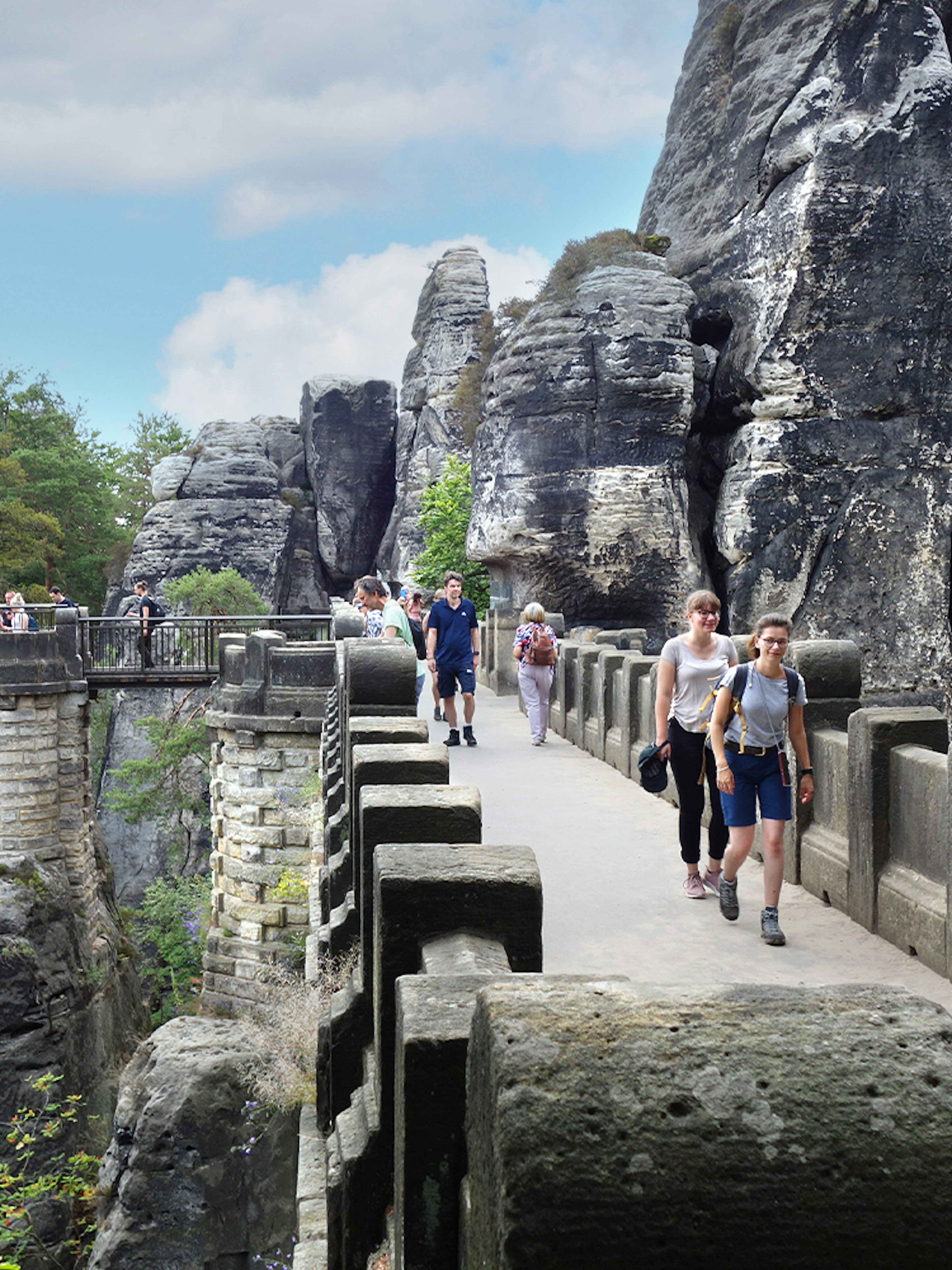 Visitors walking on Bastei Bridge with rock formations in Saxon Switzerland, Germany.