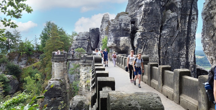 Visitors walking on Bastei Bridge with rock formations in Saxon Switzerland, Germany.