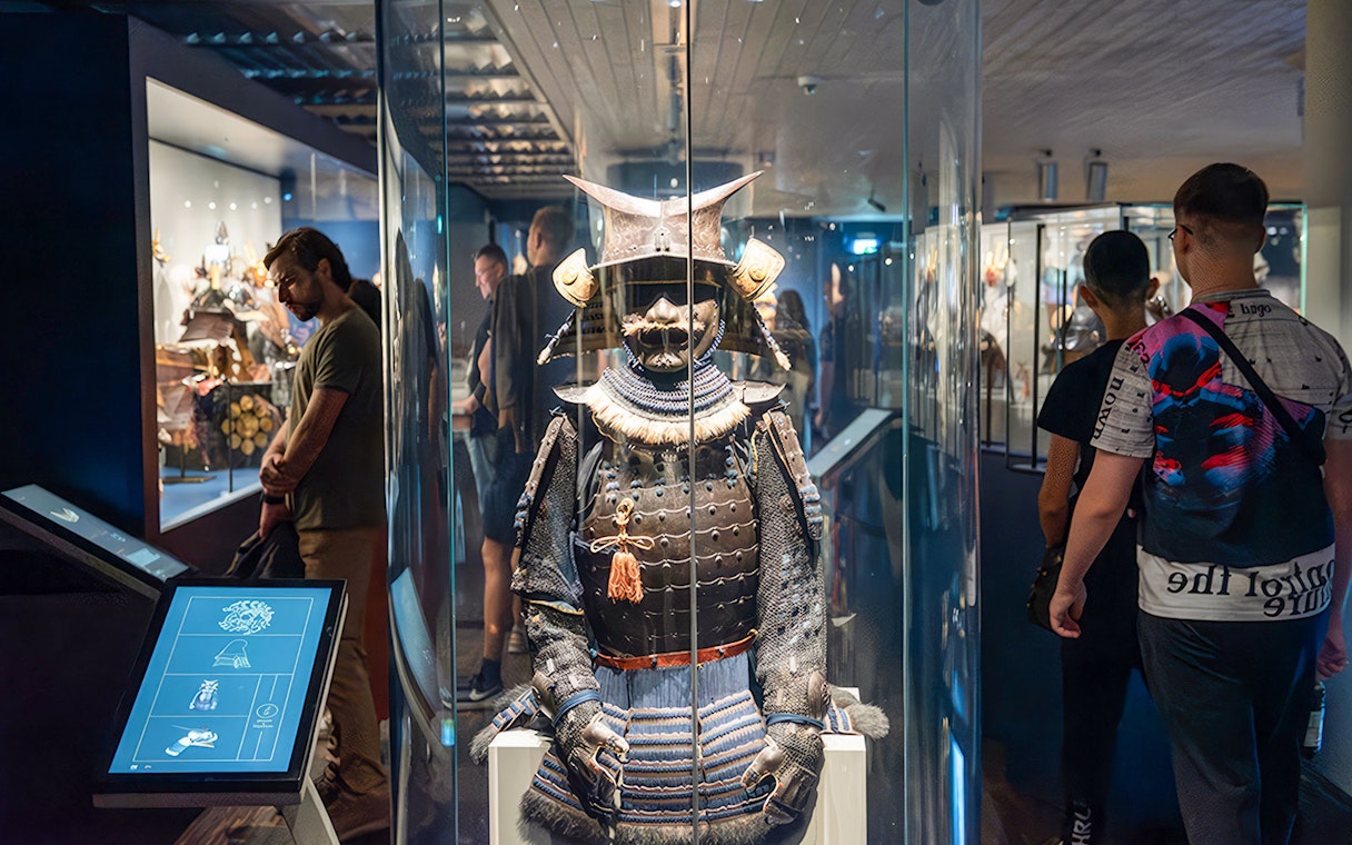 Samurai armor display at the Samurai Museum with visitors exploring exhibits.