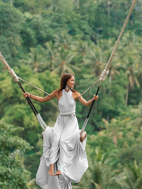 Person on a swing overlooking lush greenery in Kintamani during sunrise tour.