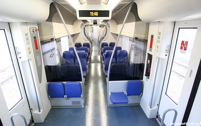 Interior of a train with blue seats, connecting Fiumicino Airport and Rome Termini Station.