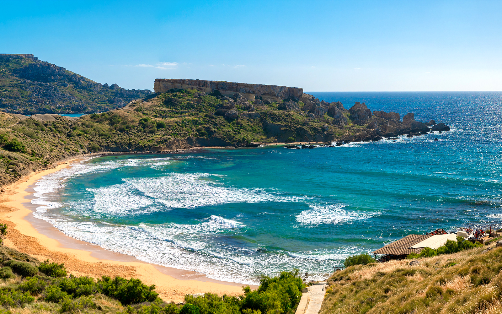 Golden Bay beach with clear waters and sunbathers, Malta.