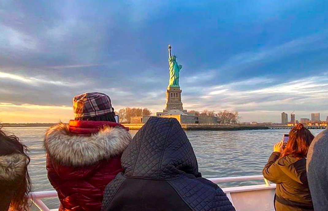 Sunset view of the Statue of Liberty from the Ellis Island Sunset Cruise, a unique New York City tour experience