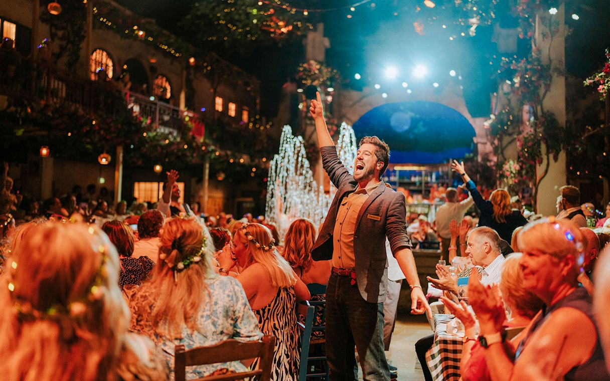 Performer engaging audience at Mamma Mia! The Party with festive atmosphere.