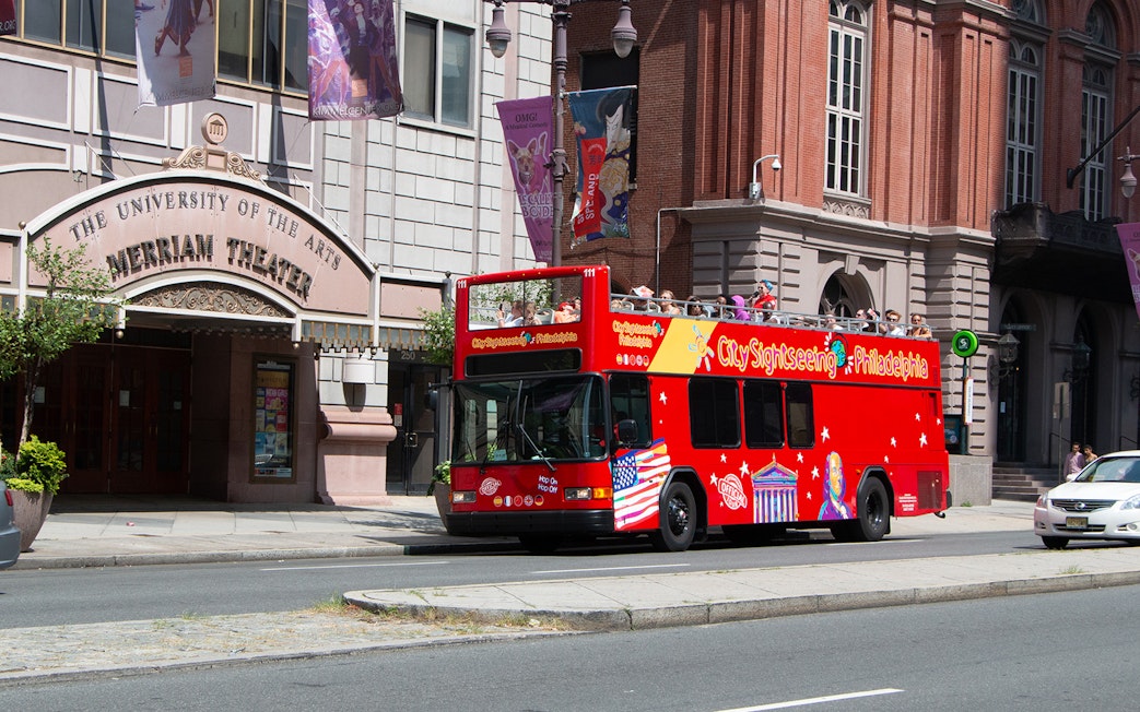 Red double-decker bus on Philadelphia Hop-On-Hop-Off Tour passing Merriam Theater.
