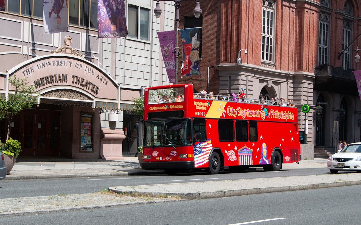 Red double-decker bus on Philadelphia Hop-On-Hop-Off Tour passing Merriam Theater.