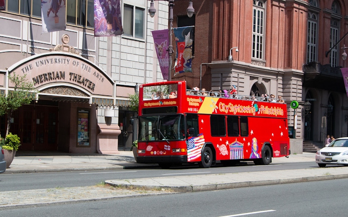 Red double-decker bus on Philadelphia Hop-On-Hop-Off Tour passing Merriam Theater.