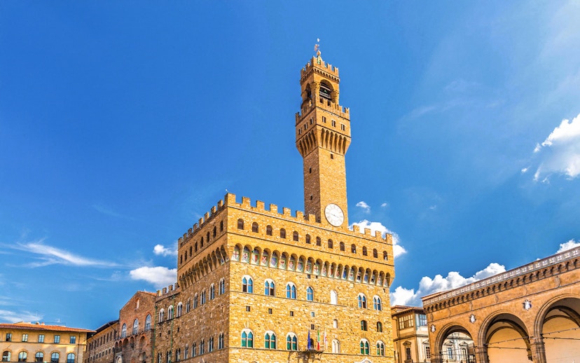 Palazzo Vecchio exterior with clock tower under clear blue sky in Florence, Italy.