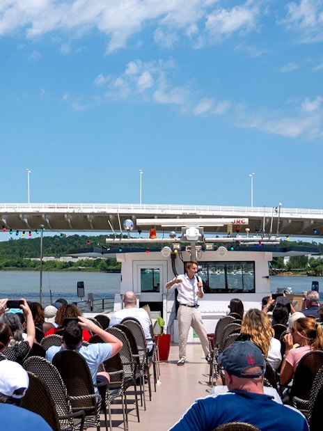 Guide giving live commentary on Bordeaux river cruise with bridge in background.