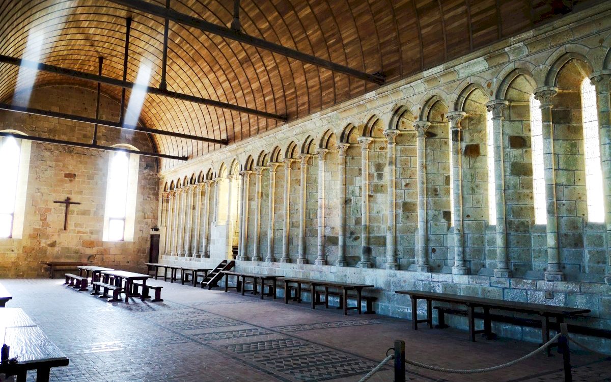 Mont-Saint-Michel Abbey interior with arched columns and wooden benches.