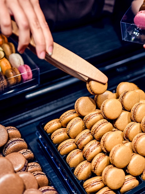 Macarons being selected during a Secret Food Tour near Notre Dame, Paris.