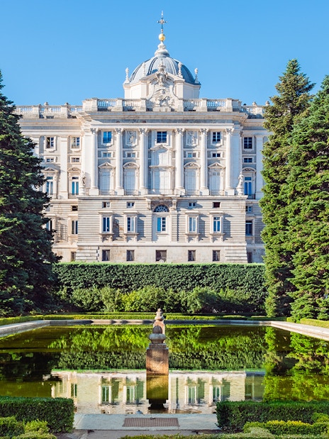 Royal Palace of Madrid with garden and reflecting pool in foreground.