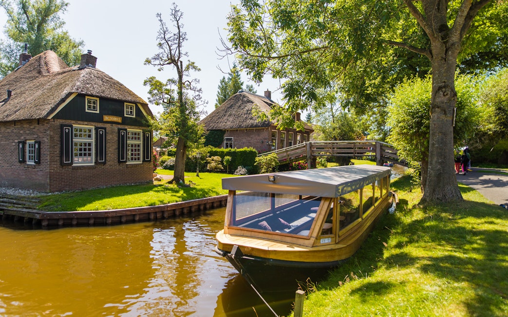 Canal boat near traditional thatched house in Giethoorn, Netherlands, on a day trip from Amsterdam.