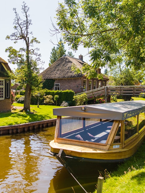 Canal boat near traditional thatched house in Giethoorn, Netherlands, on a day trip from Amsterdam.