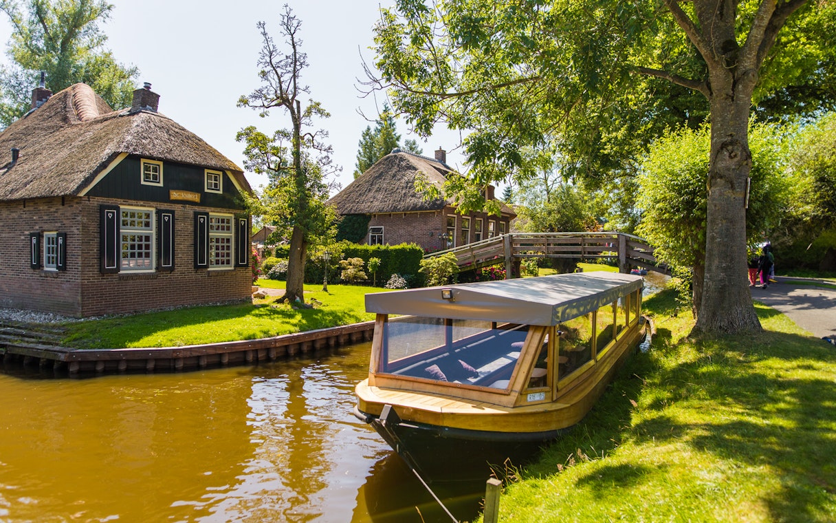 Canal boat near traditional thatched house in Giethoorn, Netherlands, on a day trip from Amsterdam.