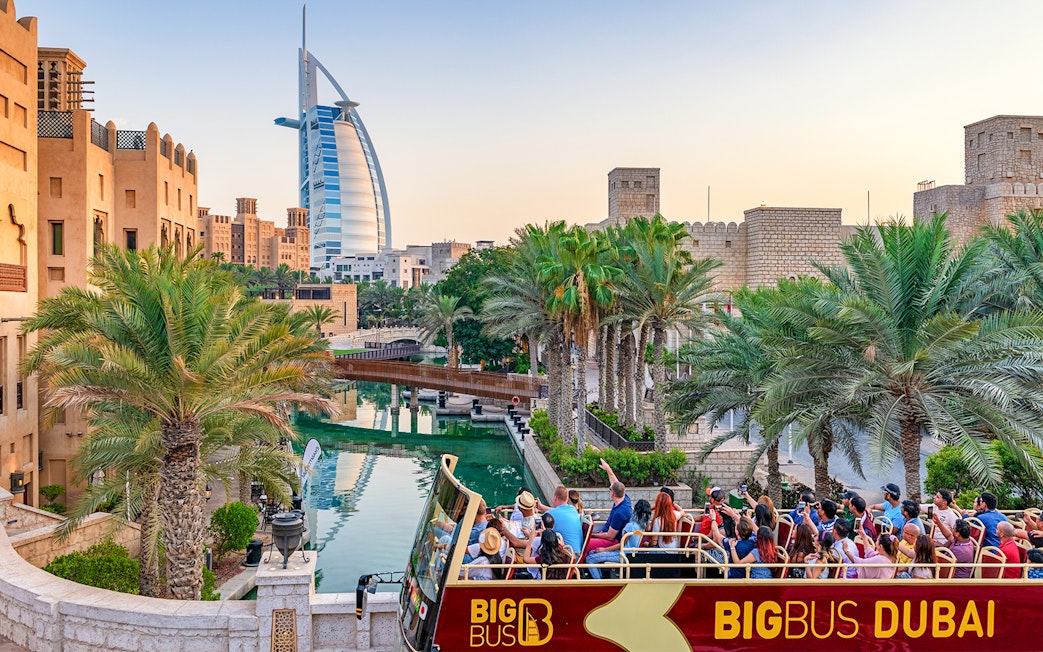 Dubai cityscape with Big Bus tour and Dhow Creek cruise in foreground.