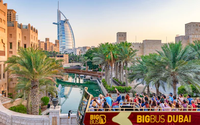 Dubai cityscape with Big Bus tour and Dhow Creek cruise in foreground.