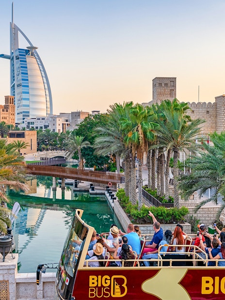 Dubai cityscape with Big Bus tour and Dhow Creek cruise in foreground.