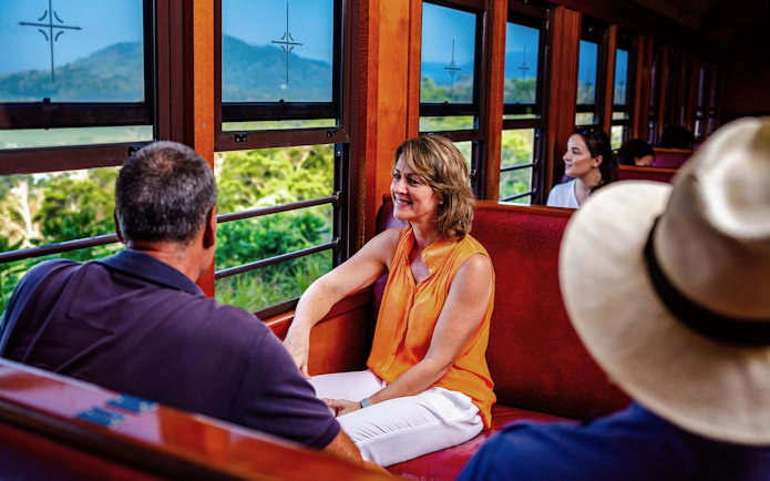 Passengers enjoying views on a scenic train tour through lush landscapes.