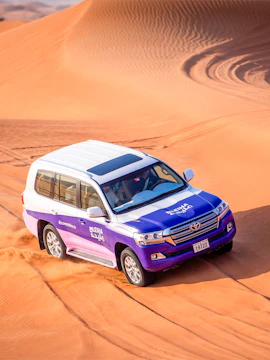 SUV driving through Mleiha desert dunes in adventure tour.