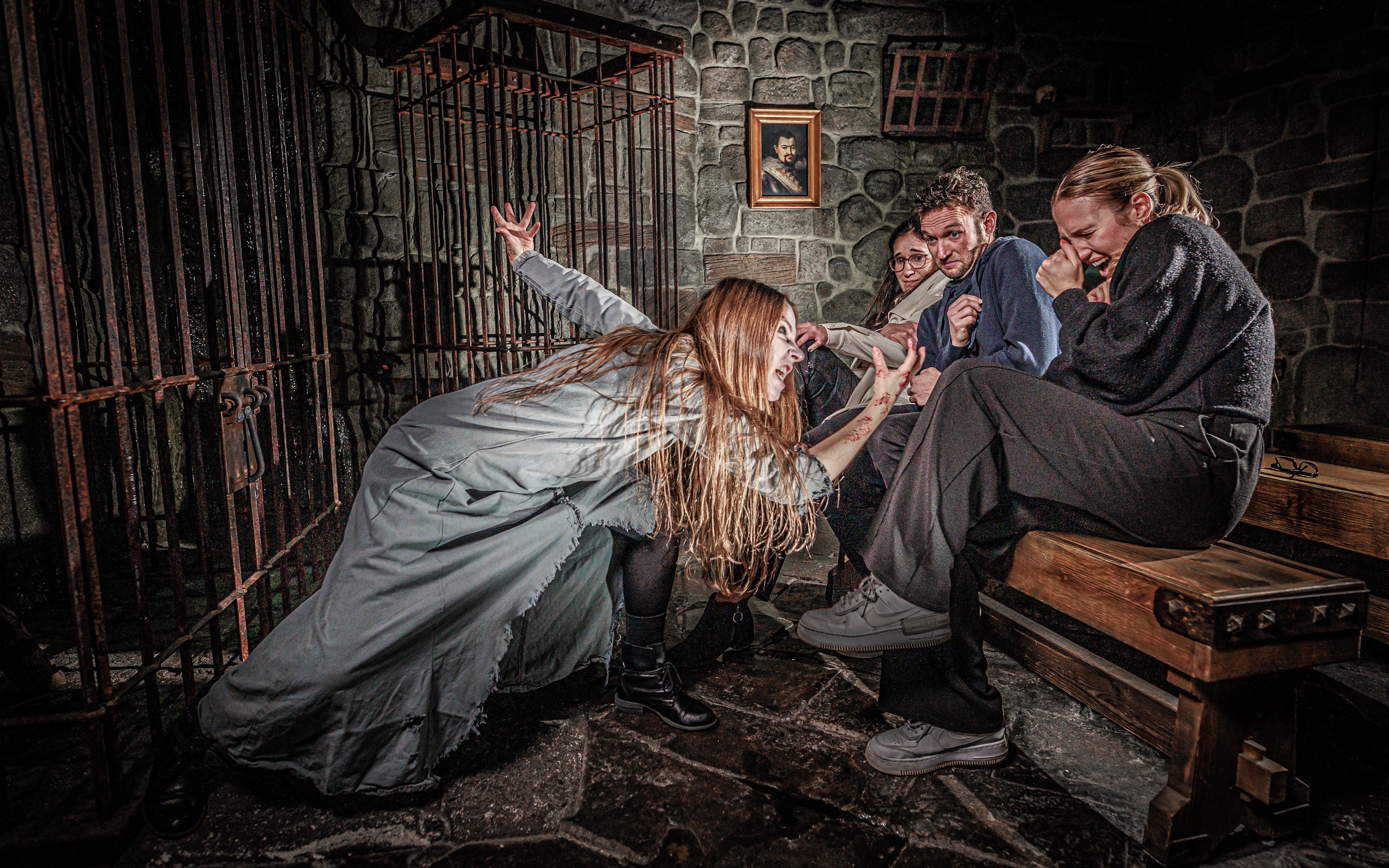 Visitors react to a performer in a spooky scene at the London Dungeon.