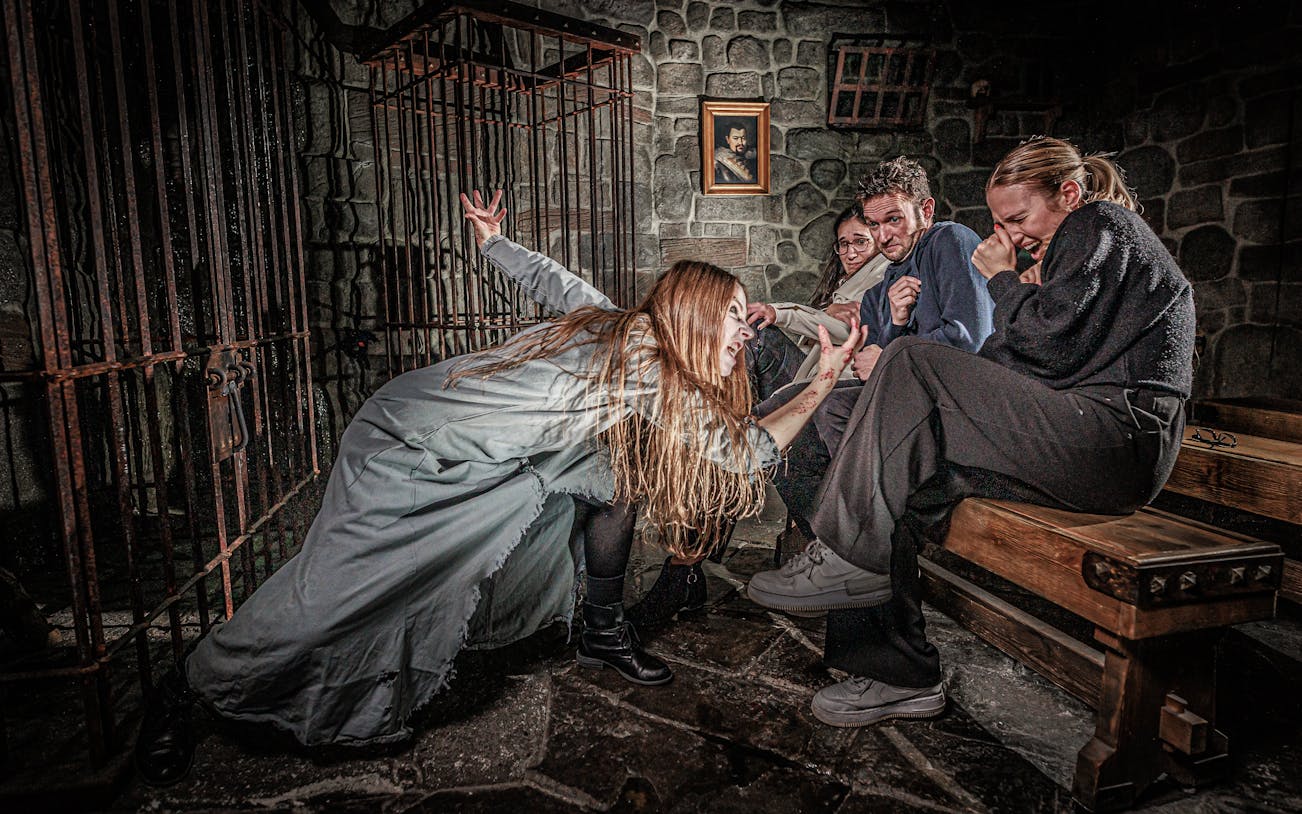 Visitors react to a performer in a spooky scene at the London Dungeon.
